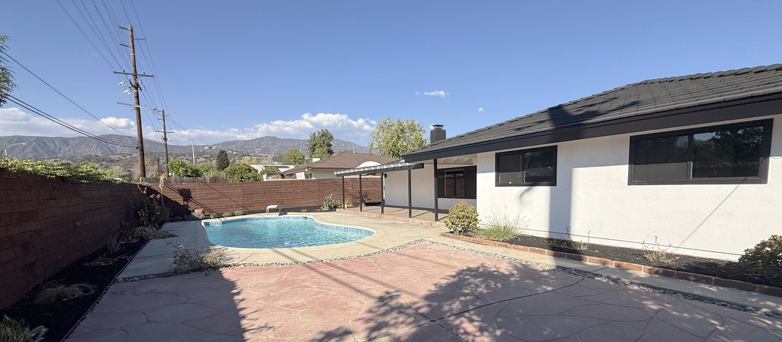Rear yard looking toward the mountains, with the pool, wood privacy fence, and stamped concrete