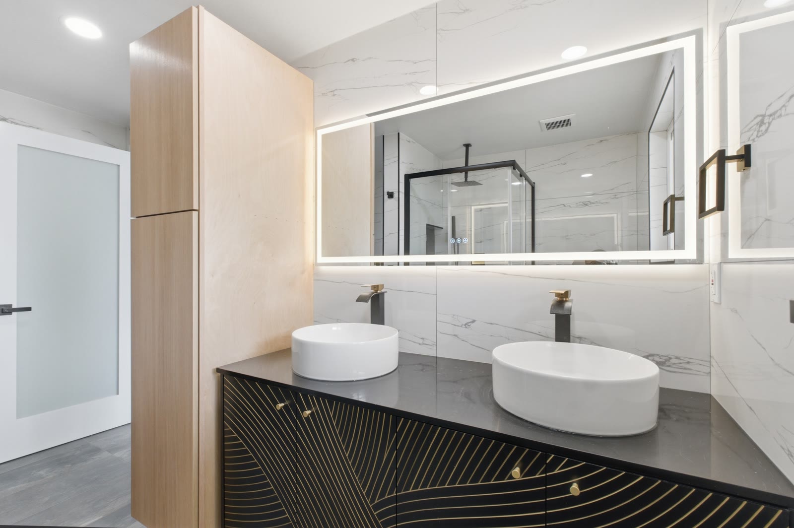 Primary bath vanity — twin vessel sinks on a fluted base, LED mirror, tall wood storage tower