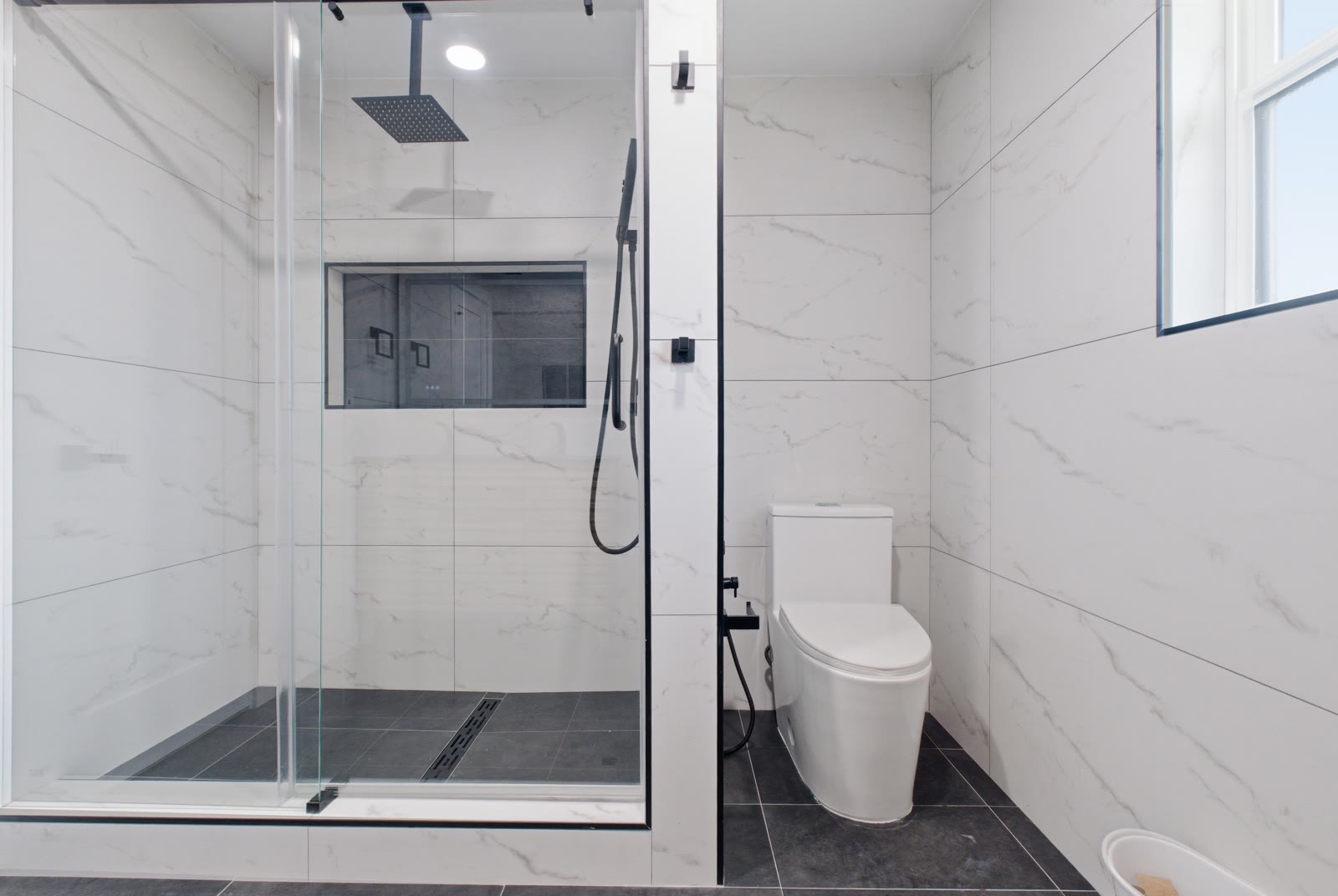 Secondary bath — walk-in glass shower with rainfall head and tiled niche