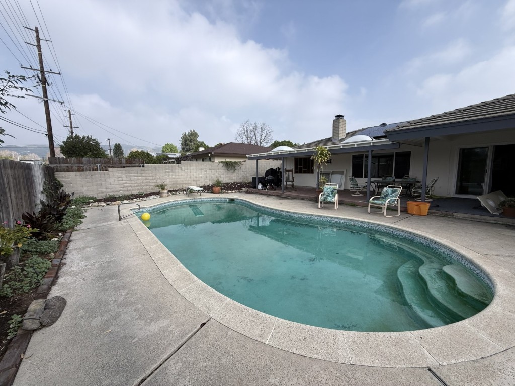 Backyard before renovation — aging pool coping, plain block wall, overcast day