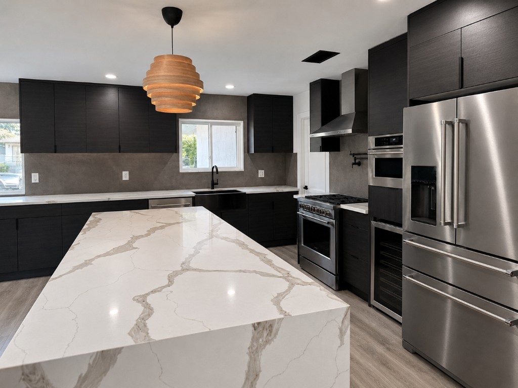 Kitchen after renovation — waterfall quartz island, dark Euro-style cabinetry, KitchenAid appliances