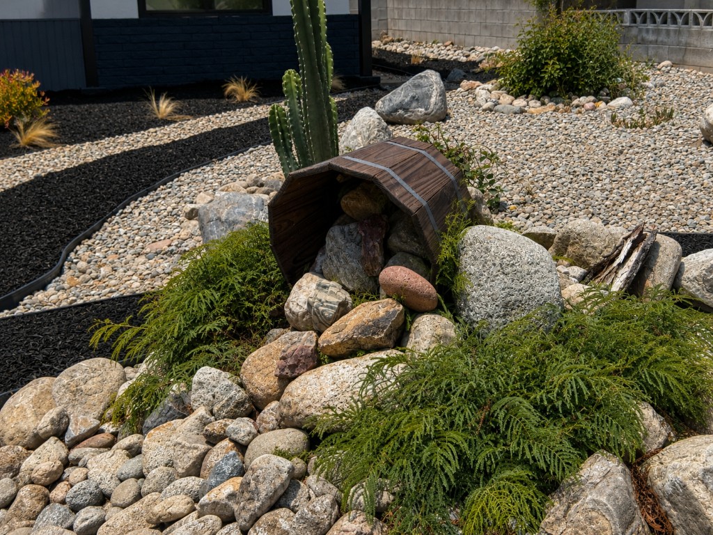 Low-maintenance dryscape front yard — gravel, rock formations, curated plants