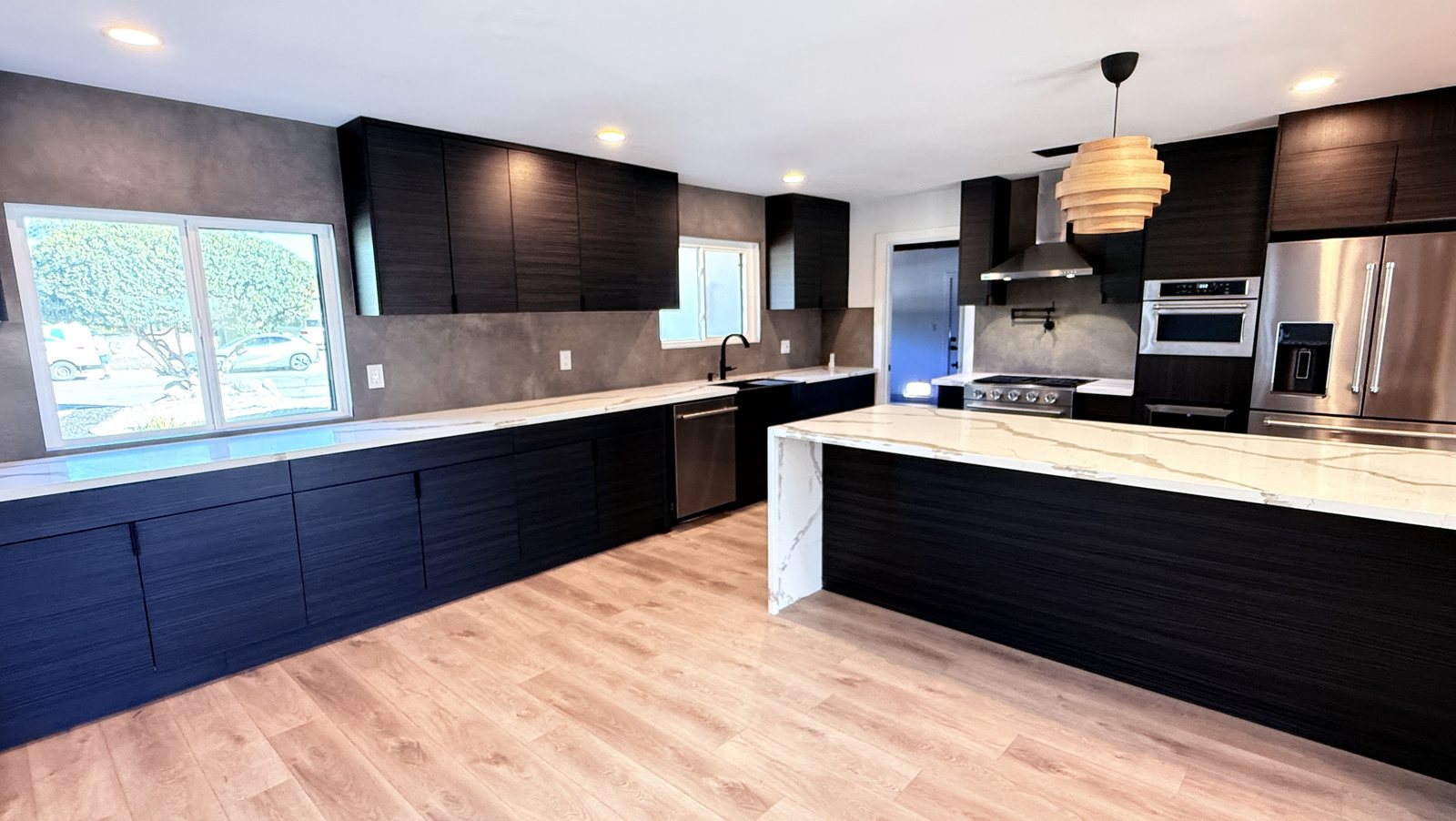 Kitchen cabinet run under the front window, full-height tile backsplash, waterfall quartz island, range with pot filler, stainless appliances