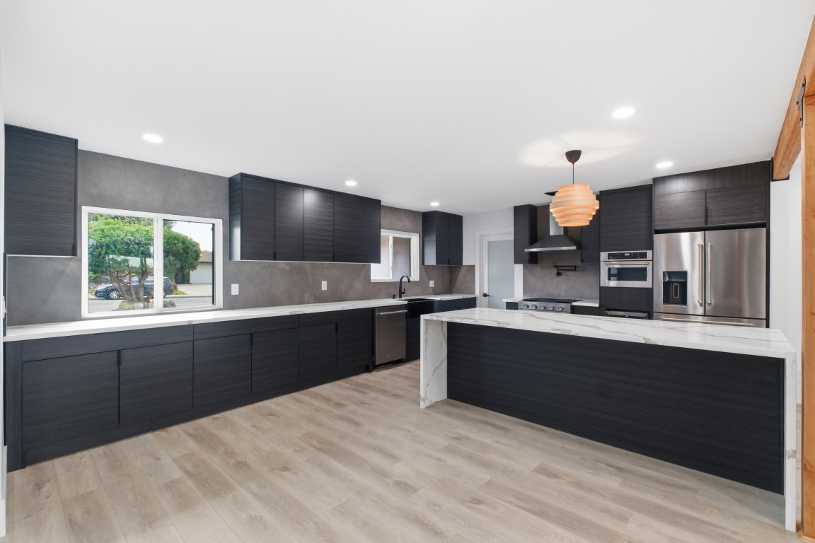 Full L-shaped kitchen — long cabinet run, island at right, window over the sink