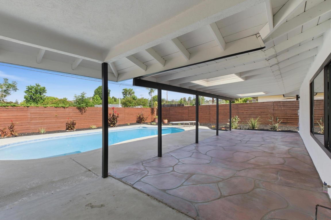 Full-length covered patio with stamped concrete, looking out over the pool