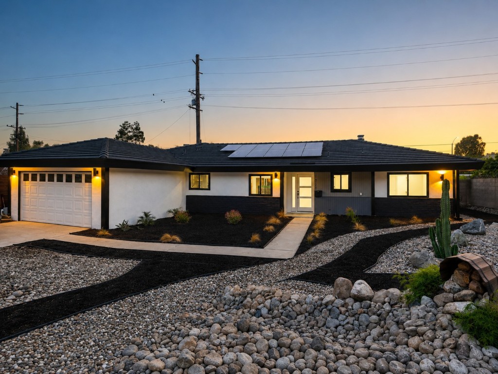 1921 Wheaton Avenue at twilight — single-story home with lit windows, rooftop solar panels, and dryscape front yard under a sunset sky